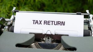 a close up of a typewriter with a tax return sign on it
